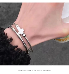 Silver bamboo joint bangle and beaded cross pendant bracelet set worn on wrist