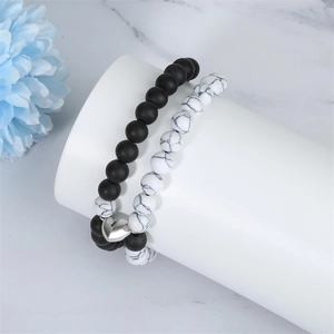 Detail of adjustable magnetic heart clasps connecting black and white beaded bracelets