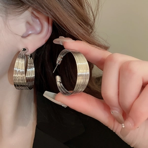 Detail of silver multi-layer hoop earrings with polished metallic finish on a model