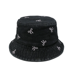 Detail of pink embroidered bows on black denim fisherman hat with twill fabric texture