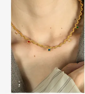 Close-up of a gold wave chain necklace with five square-cut colorful zircon gemstones