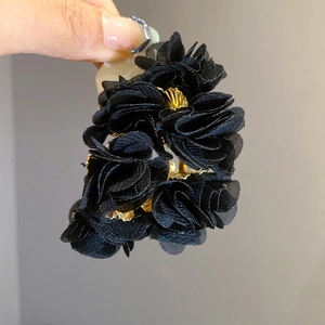 Detailed view of handmade black mesh flower hair claw with gold center accents