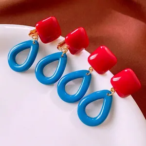 Retro square red and waterdrop blue resin earrings with golden metal links on a tray