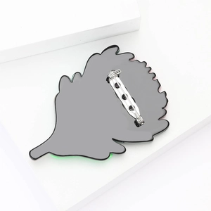Detailed back view of leaf-shaped brooch with silver pin fastener and grey metal base