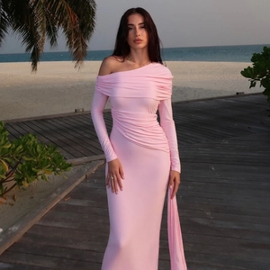 Pink one-shoulder maxi dress with ruched details and side slit on a beach boardwalk