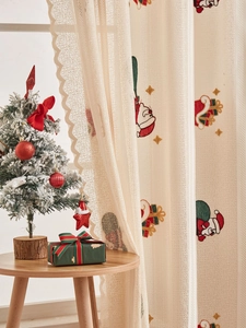 Detailed embroidery of Santa and gifts on cream lace semi-sheer Christmas curtains