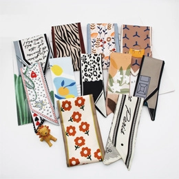 Dettaglio di vari foulard sottili in seta con motivi floreali, leopardati e con lettere