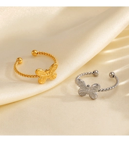 Detail view of gold and silver butterfly rings with twisted rope band on silk fabric