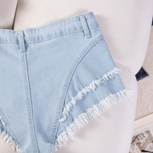 Dettaglio di pantaloncini in denim azzurro con orli sfilacciati e cuciture diagonali definite
