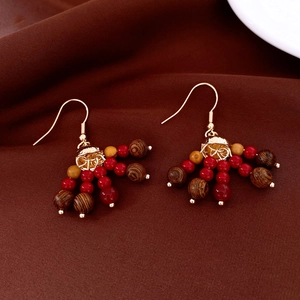 Détails de boucles d'oreilles dorées vintage avec perles rouges, jaunes et bois sur velours