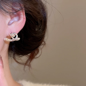 Détail de la boucle d'oreille nœud torsadé argenté portée avec fini poli