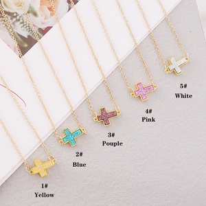 Detailed flat lay of colorful glittery cross pendants on gold chains for women