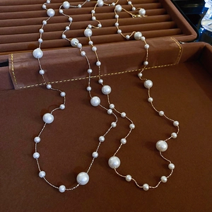 Elegant gold double layer pearl necklace displayed on a brown jewelry tray