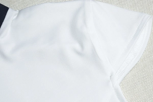 Close-up of white piqué knit polo sleeve with navy blue contrast trim on the collar