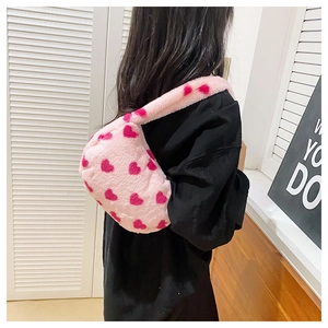 Detailed close-up of a pink plush shoulder bag featuring vibrant red heart patterns