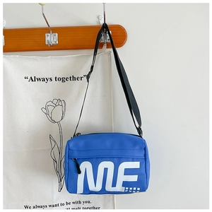 Gros plan d'un sac bandoulière enfant bleu roi avec lettres ME sur crochet en bois