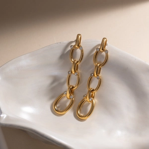 Gros plan de boucles d'oreilles pampilles dorées avec anneaux ovales et strass brillants