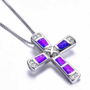 Detailed macro view of silver cross pendant with purple opal inlay and rhinestone accents