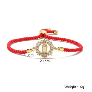 Macro view of 18K gold Virgin Mary pendant with white zircons on red rope bracelet