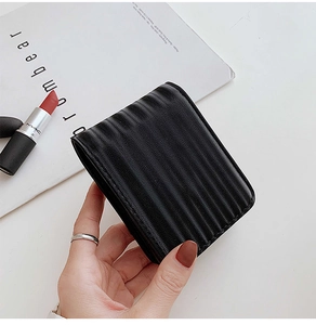 Close-up of a mini black striped lipstick case with mirror held by a hand