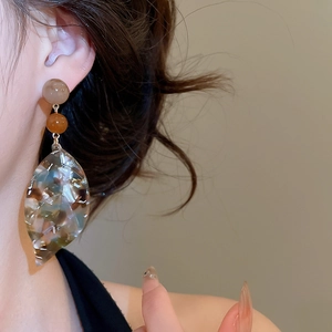 Detail of vintage style acetate leaf pendant earrings with marble texture on model