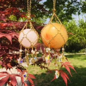 Detailed view of pink and orange crystal net pendants with gold chains and star charms