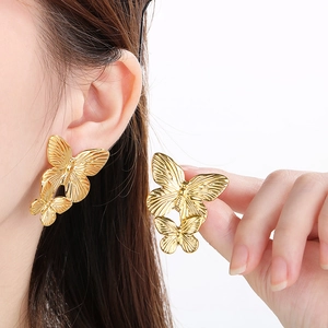 Detail shot of golden double-layered butterfly stud earrings with vintage texture