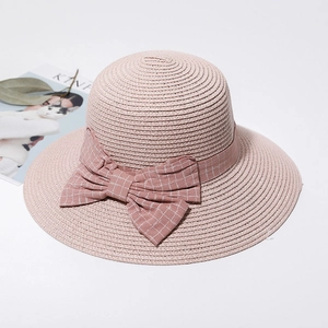 Close-up of pink straw sun hat showing woven texture, plaid ribbon, and large bow detail