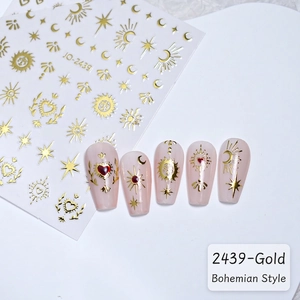 Macro shot of gold bohemian star and moon nail stickers on soft pink nails