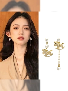 Detailed view of asymmetric gold rocking horse earrings with pearls and crystals