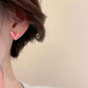 Close-up of elegant pink heart pearl stud earring with golden rim on woman ear