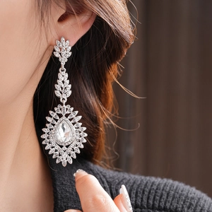 Close-up of elegant silver drop earrings with crystals and leaf motifs worn by a model