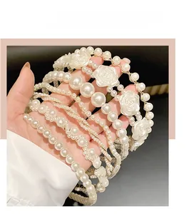 Detailed view of elegant white pearl headbands with camellia flower accents and vintage finish