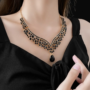 Detailed view of a V-shaped necklace with a large black teardrop pendant on a model