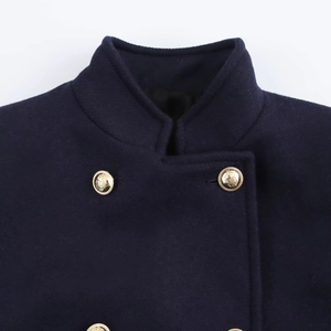 Detail of navy blue wool coat featuring double-breasted collar and gold embossed buttons