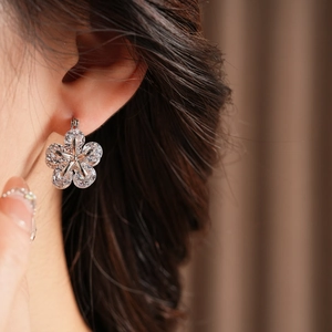 Gros plan de boucles d'oreilles fleur en zircon élégantes portées sur l'oreille