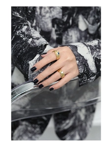 Detail of two gold irregular textured rings with blue and clear zircon gems on fingers
