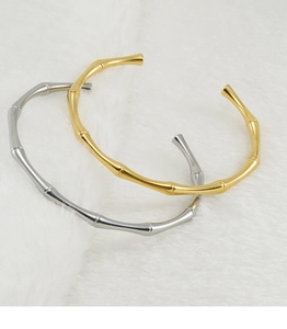 Dettaglio dei bracciali aperti stile bambù in oro e argento con lucentezza metallica