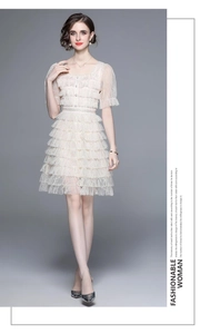 Détails de robe en dentelle beige avec jupe à volants et encolure carrée élégante