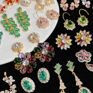 Boucles d'oreilles et bagues fleurs plaquées or avec zircons colorés sur une assiette blanche