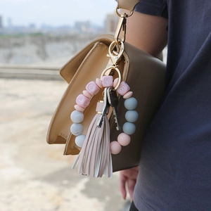 Silicone bead keychain with pink grey beads and beige tassel on a stylish handbag