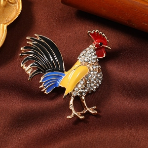 Exquisite rooster brooch with colorful enamel and sparkling rhinestones on vintage fabric