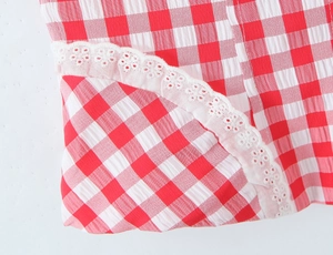 Dettaglio macro del tessuto vichy rosso e bianco con ricamo in pizzo bianco rifinito