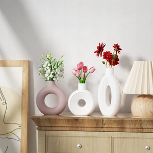 Minimalist ring-shaped ceramic vases in matte pink and white with floral arrangements