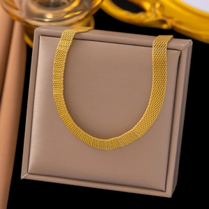 Macro detail of golden mesh chain necklace showing woven texture on a dark jewelry pad
