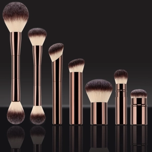 Bronze makeup brush set with gradient bristles arranged on a black reflective surface