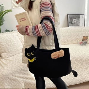 Detail of cartoon cat embroidery on black canvas tote bag with plush keychain accessory
