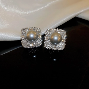 Macro shot of silver stud earrings with grey pearl and pavé zirconia on silk background