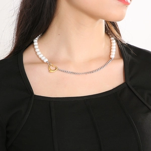 Detail of necklace featuring white pearls and silver Cuban chain with a gold heart clasp