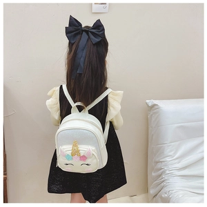 Detail showing white unicorn backpack with golden horn and colorful floral decorations